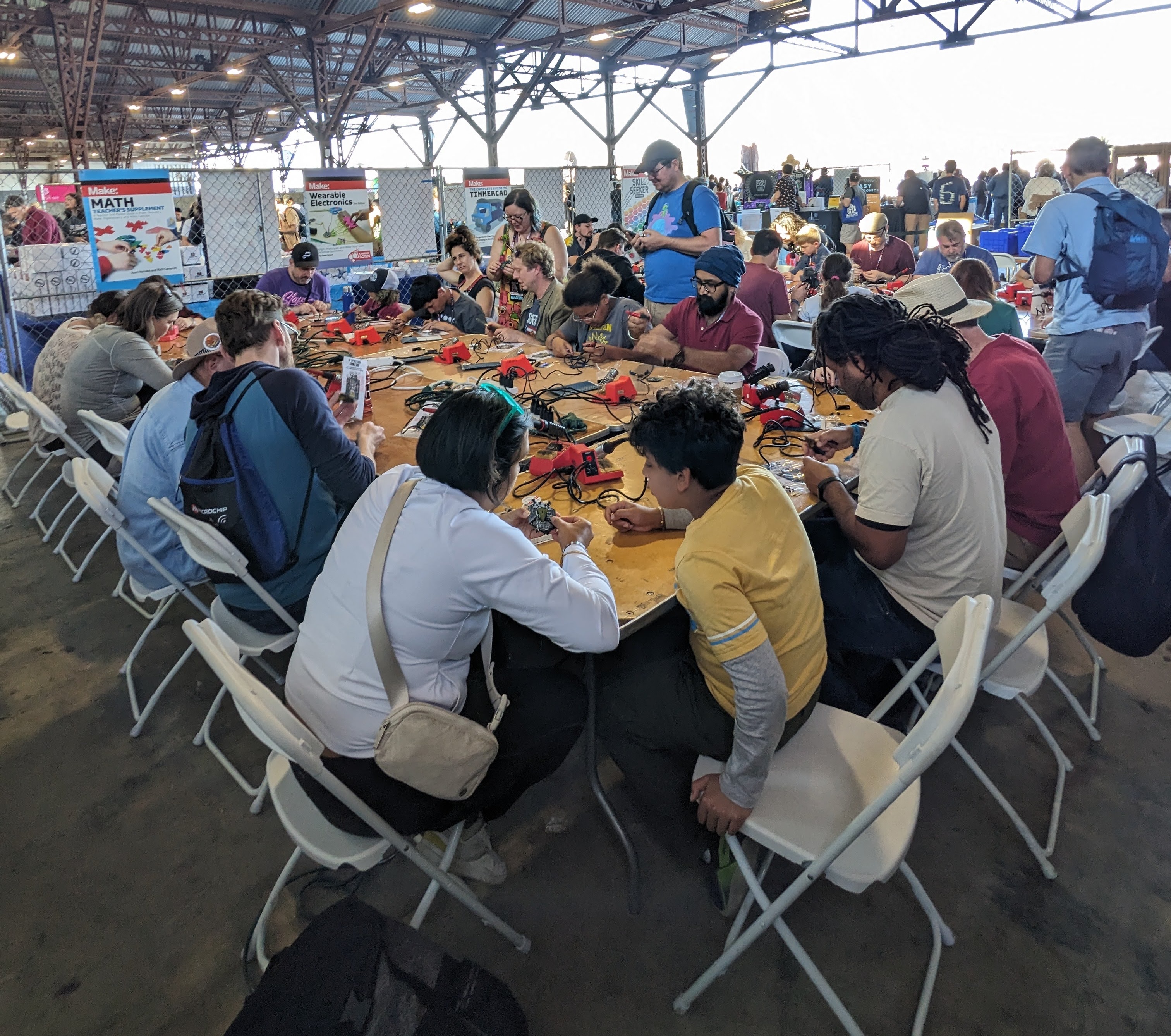 Maker Faire EMF Explorer workshop - participants soldering at long tables